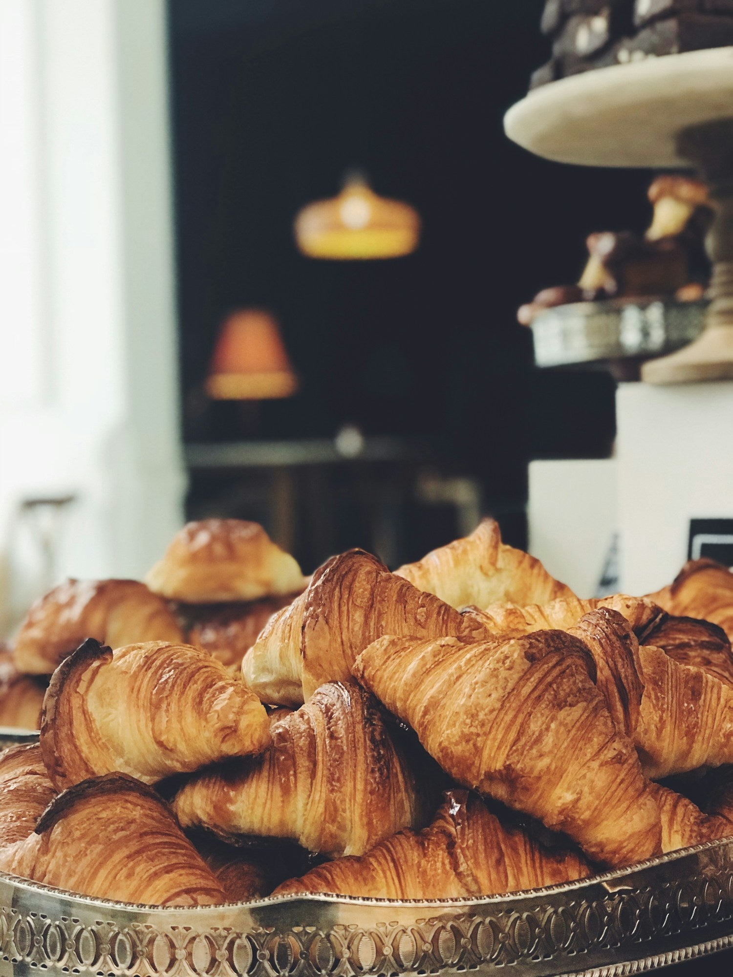 Golden croissants on an ornate silver bakery tray